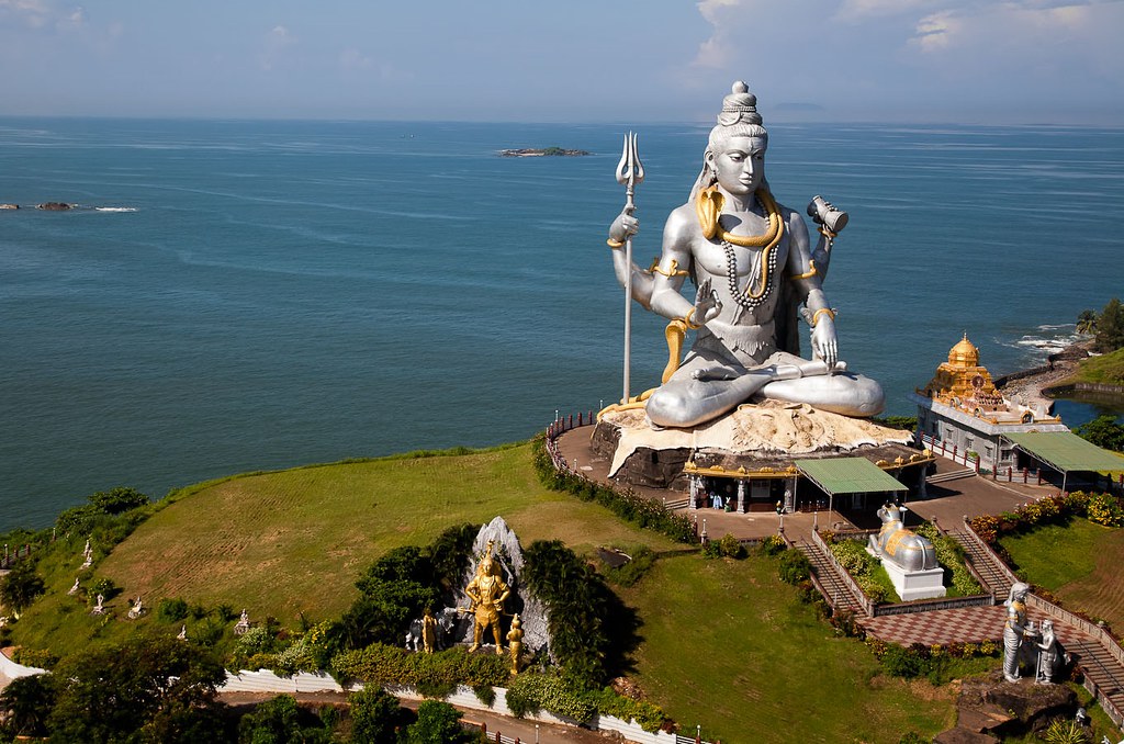Aerial view of the Murudeshwar Shiva statue on its green headland surrounded by the turquoise Arabian Sea