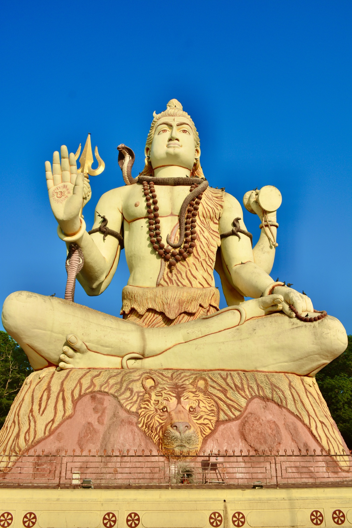 The towering seated Shiva statue at Nageshwar Jyotirlinga, Dwarka, against a vivid blue sky